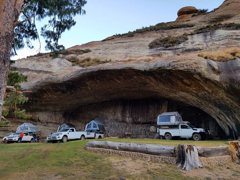 Bakkies with AHA campers camped under a large sandstone overhang.