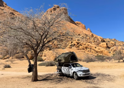 AHA Transformer on a white Ford Ranger bakkie, setup for camp (at Spitzkoppe) under a tree with shade covering the canvas side of the Transformer.