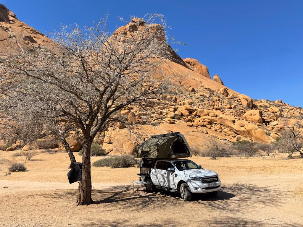AHA Transformer on a white Ford Ranger bakkie, setup for camp (at Spitzkoppe) under a tree with shade covering the canvas side of the Transformer.