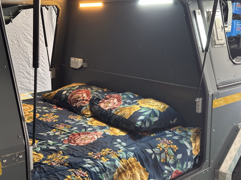 The lower bed in the AHA A/T Trailer nose compartment The made-up lower bed in the AHA A/T Trailer nose compartment, reached at ground level.