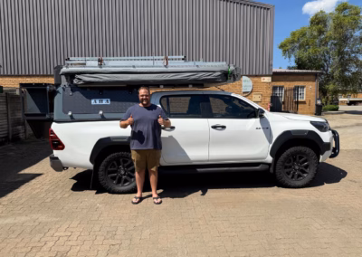 Alfons/Arnè Visser with their AHA Transformer on a Toyota Hilux Double Cab, collected at the AHA Outdoor Systems factory, 2026.