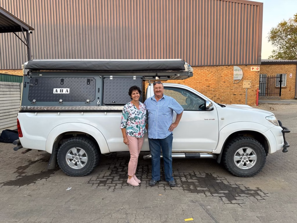 Micheal & Enell Loubsher | Toyota Hilux Single Cab | Merrydale, Northern Cape Micheal and Enell Loubsher with their AHA Transformer on a Toyota Hilux Single Cab, collected at the AHA Outdoor Systems factory, 2024.